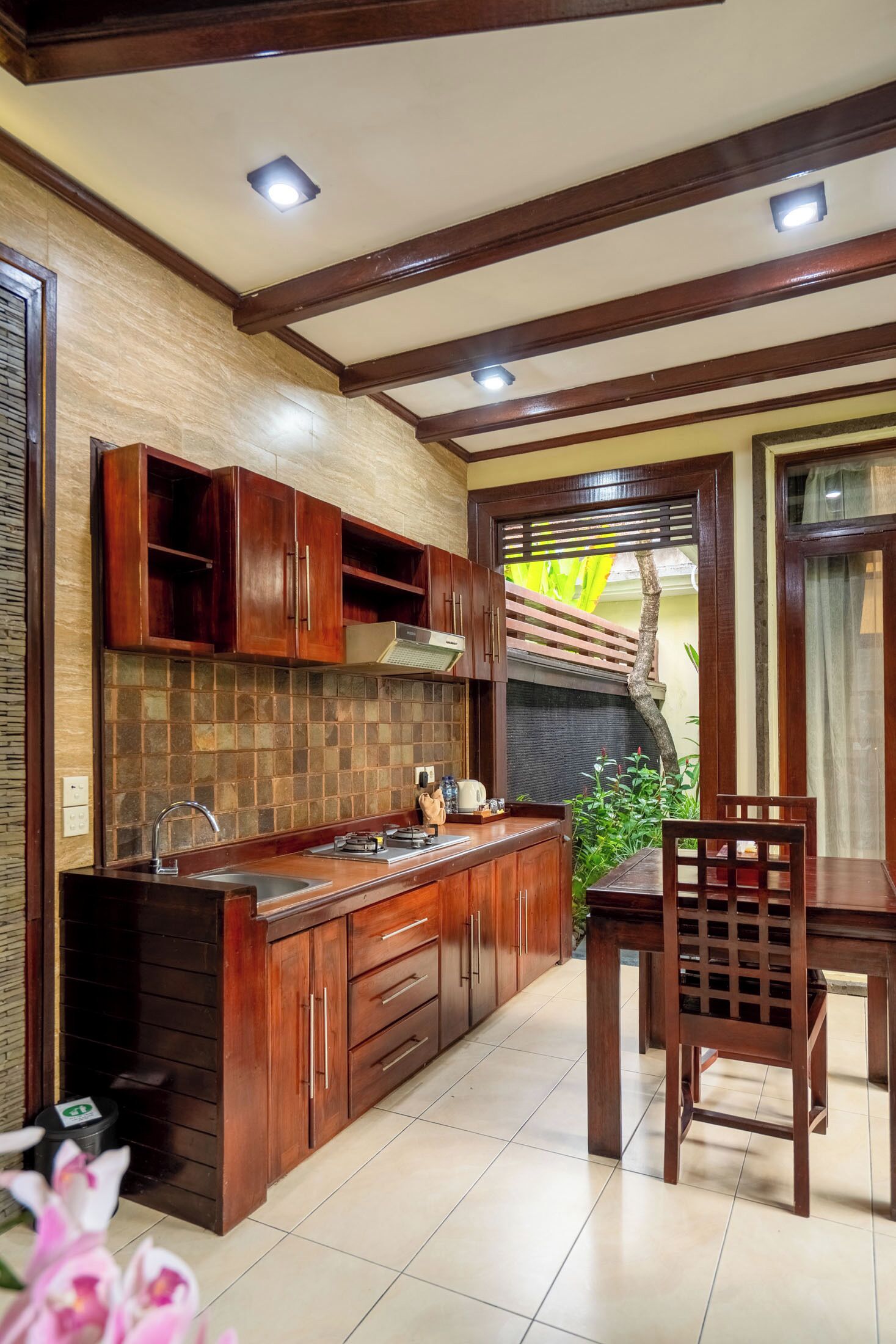 Uma cozinha com armários de madeira, painel de azulejos e uma área de jantar com mesa e cadeiras.