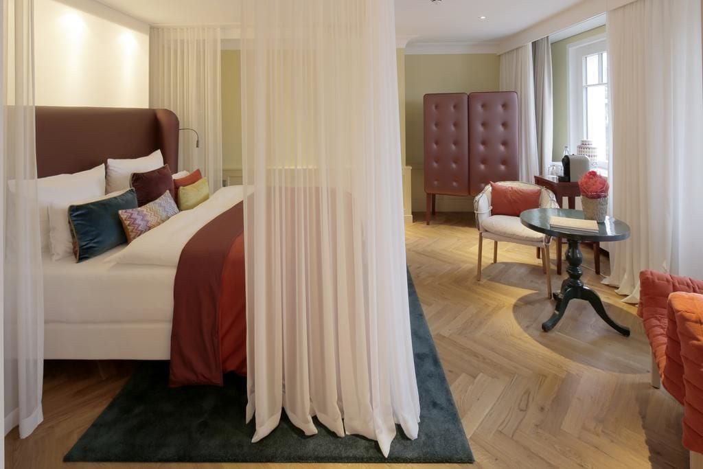 Una habitación de hotel con una cama, una silla, una mesa y un ventanal grande.