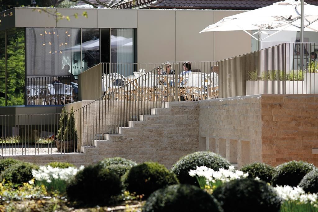 Ein zeitgemäßer Außenbereich mit Treppe zu einer überdachten Terrasse.