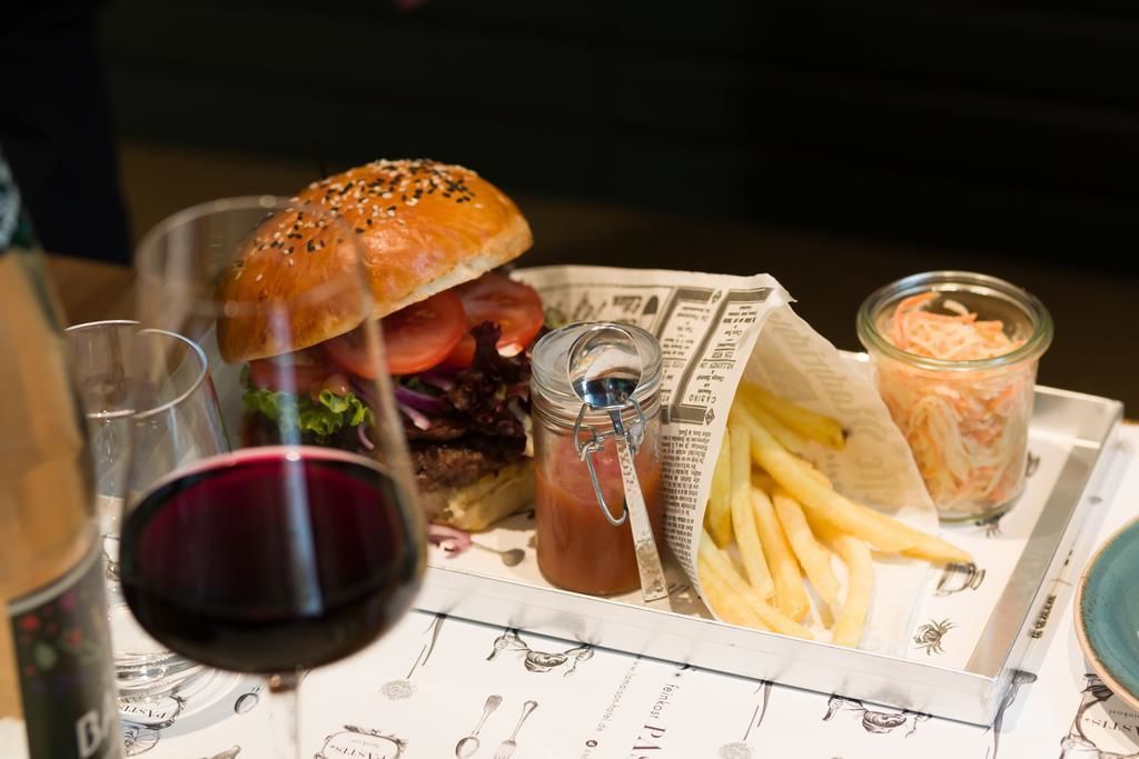 Una bandeja con una hamburguesa, papas fritas y una bebida, junto a un periódico.