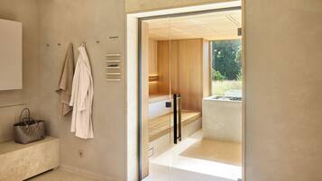 Un baño moderno con un banco de madera, un perchero y una puerta de cristal que da a la zona de la ducha.