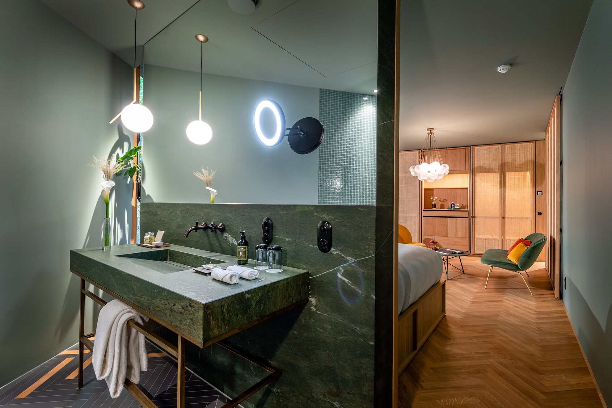 Een moderne badkamer met een marmeren wastafel, een grote spiegel en een ronde lamp.