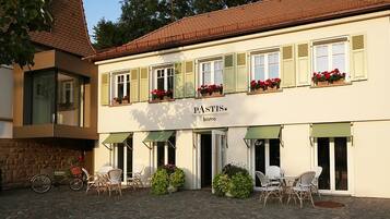A bistro named "PASTIS" with outdoor seating and a stone facade.