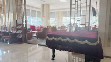 A hotel lobby with a reception desk, seating area, and large windows.
