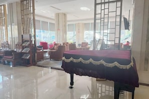 Un vestíbulo de hotel con recepción, zona de estar y amplias ventanas.
