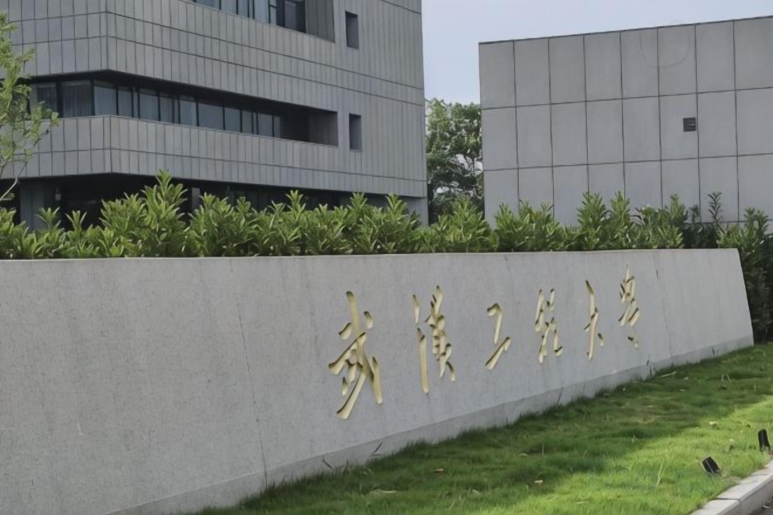 A building with a sign in gold characters, surrounded by a low hedge and grass.