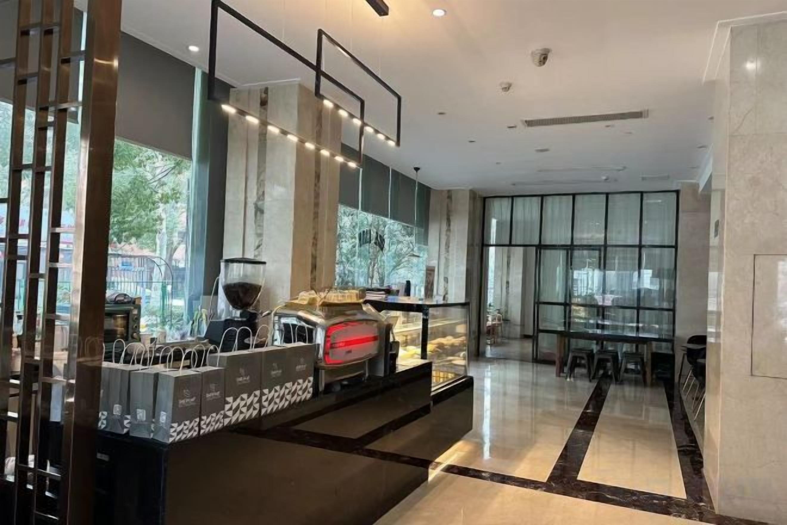 Un hall d’hôtel moderne doté d’un espace café, d’un coin salon et de grandes fenêtres.