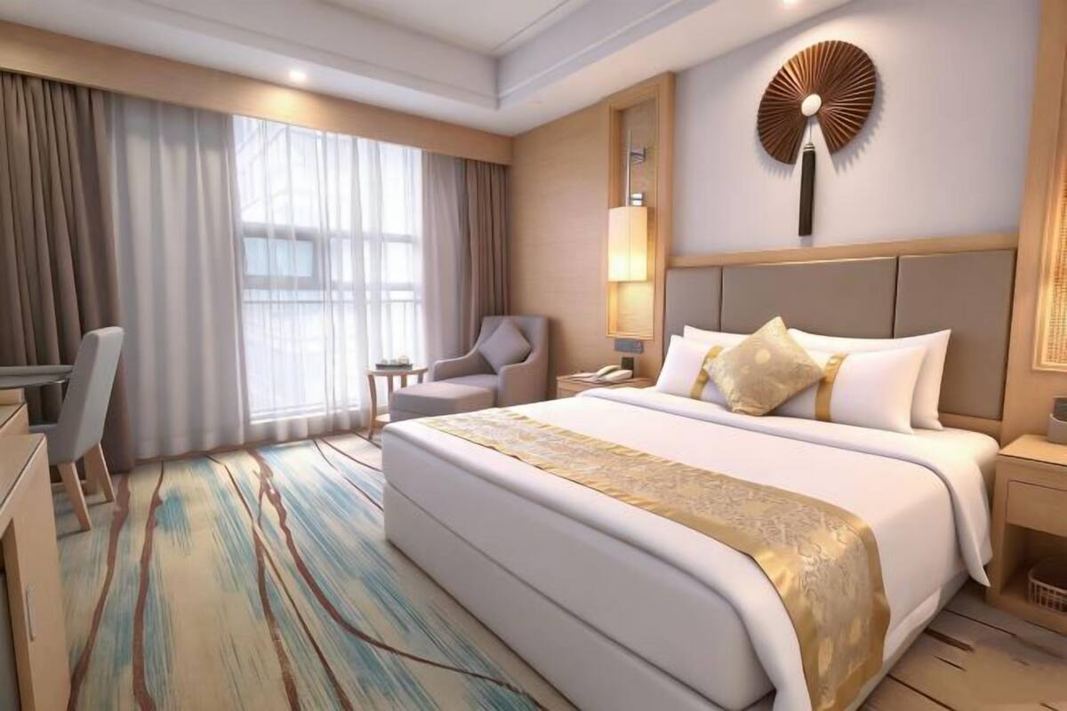 Ein Hotelzimmer mit einem großen Bett, einem Schreibtisch, einem Stuhl, einer Lampe und einer Wanddekoration.
