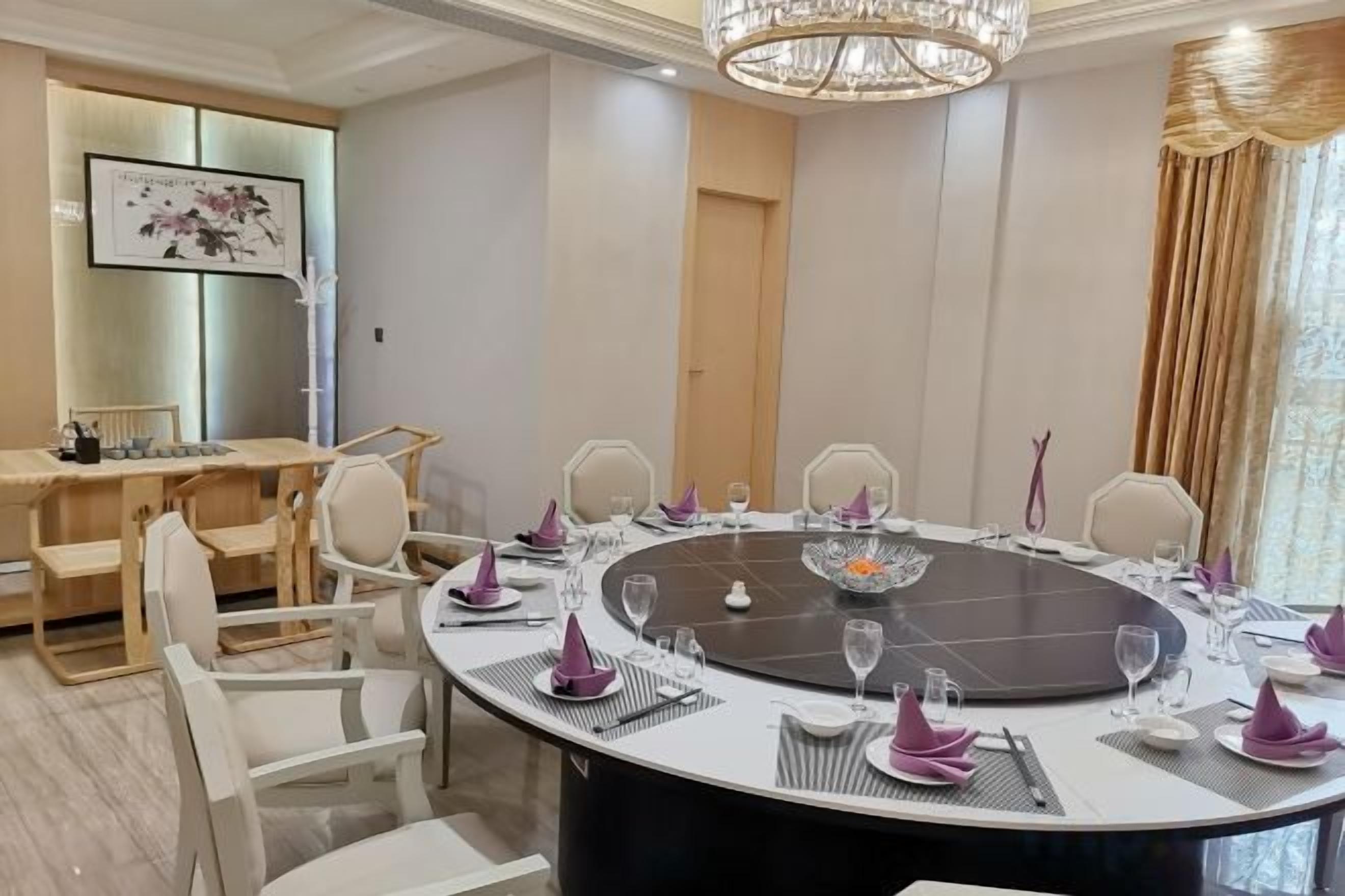 Une salle de conférence avec une table ronde, des chaises et un lustre.