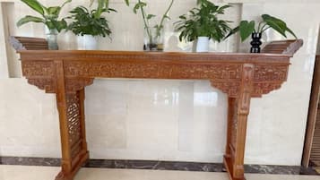 A wooden table with intricate carvings, flanked by potted plants.