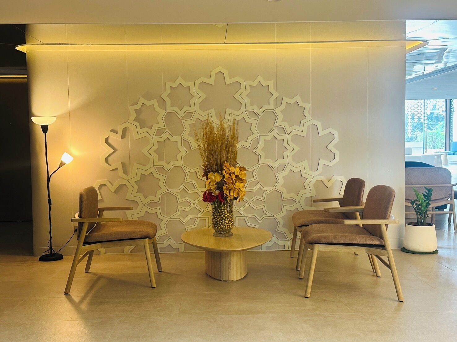 A modern lobby with a round table, two chairs, and a decorative wall with geometric patterns.
