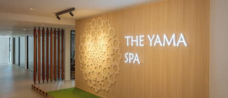 Una entrada de spa moderna con un muro de madera y un panel metálico decorativo.