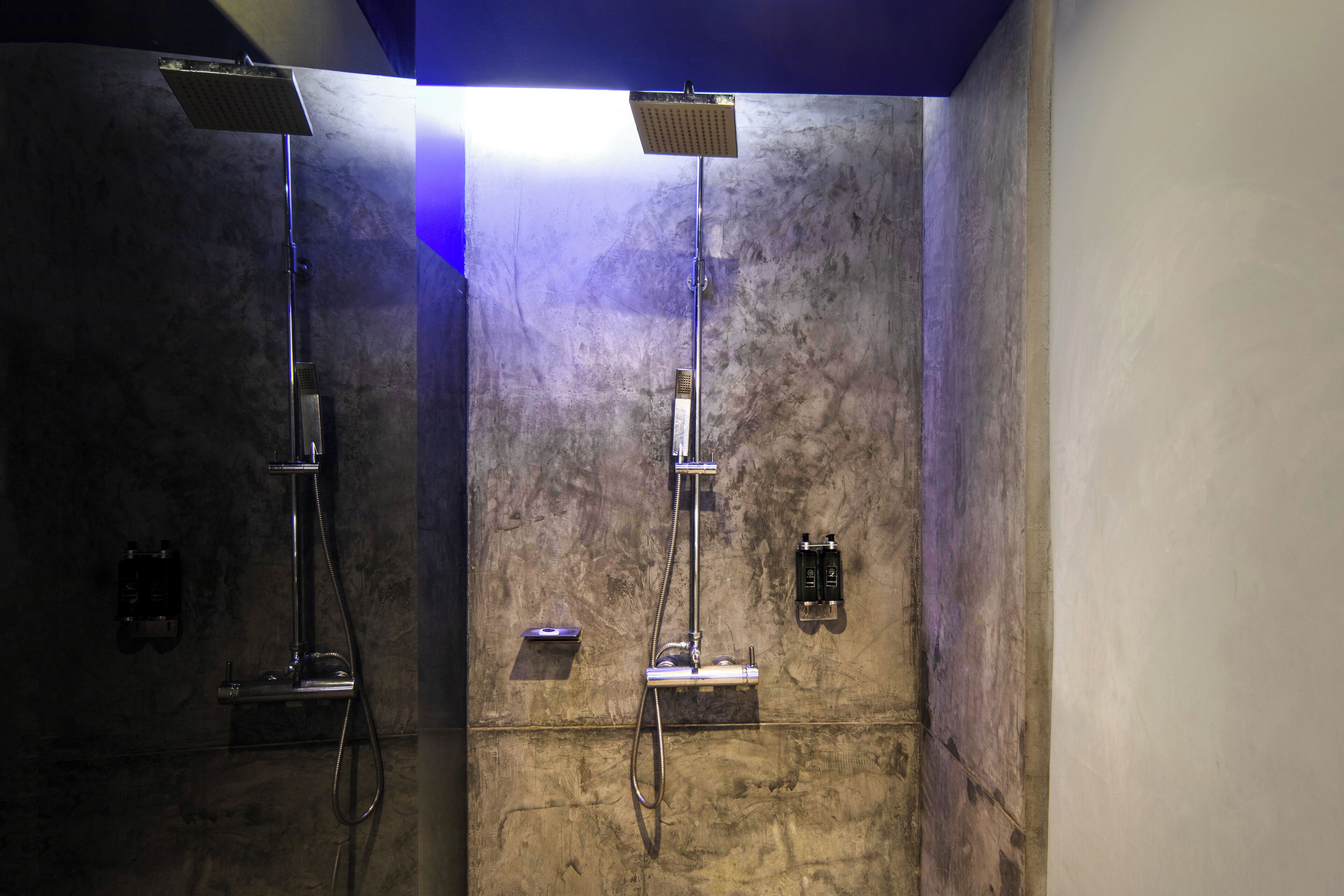 Een moderne badkamer met twee aparte douchecabines, elk voorzien van een handdouche en een handmixer.