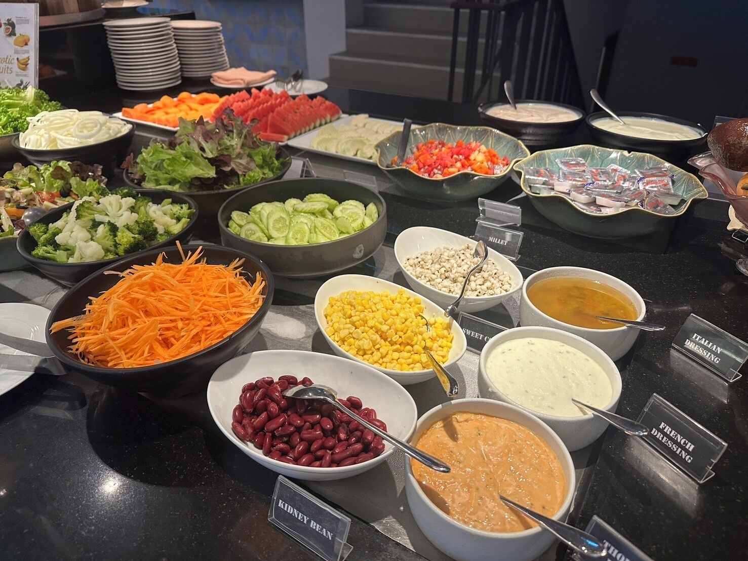 A buffet with various food items including salads, vegetables, beans, and dressings.