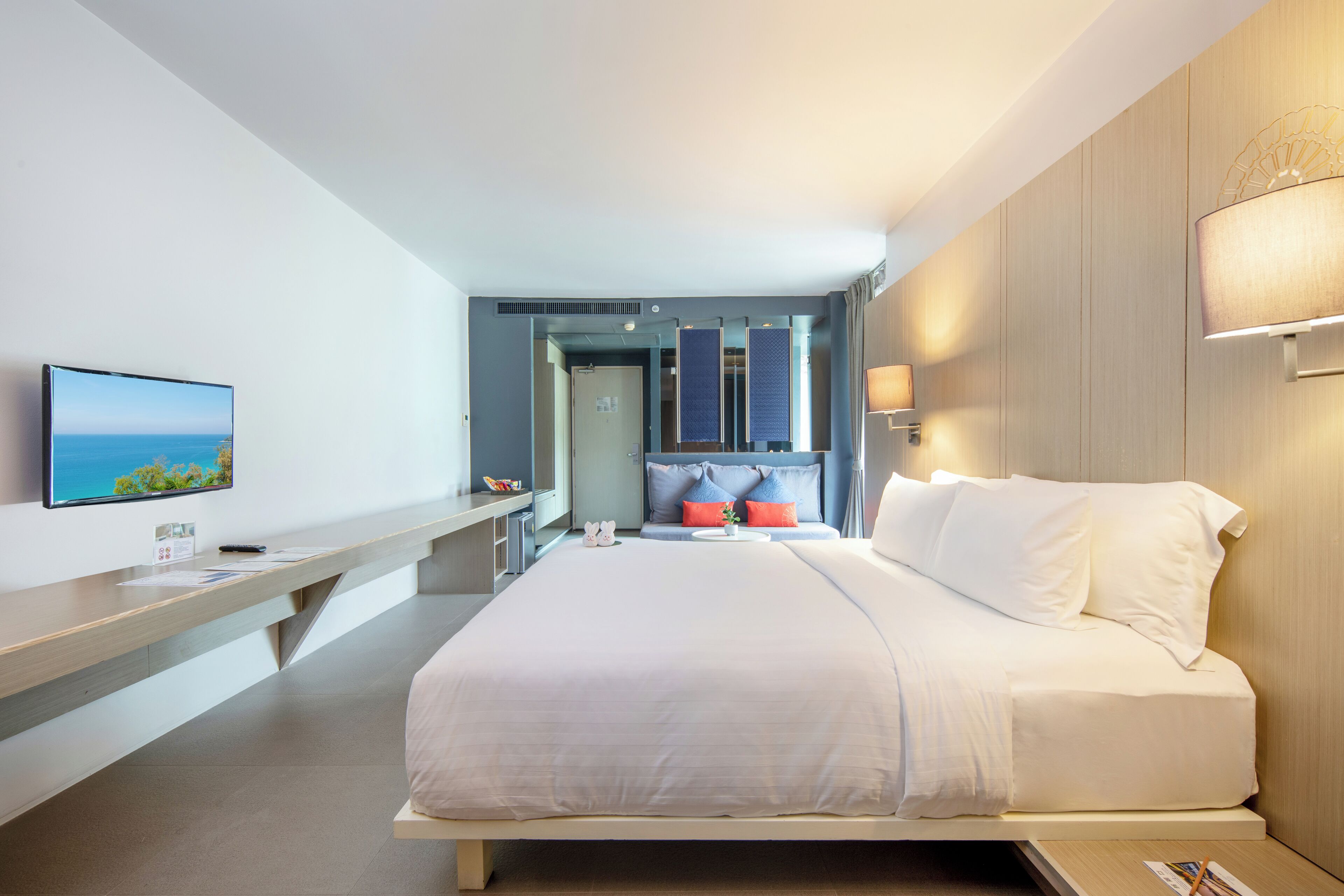 Una habitación de hotel moderna con una cama grande, un escritorio y una televisión en la pared.
