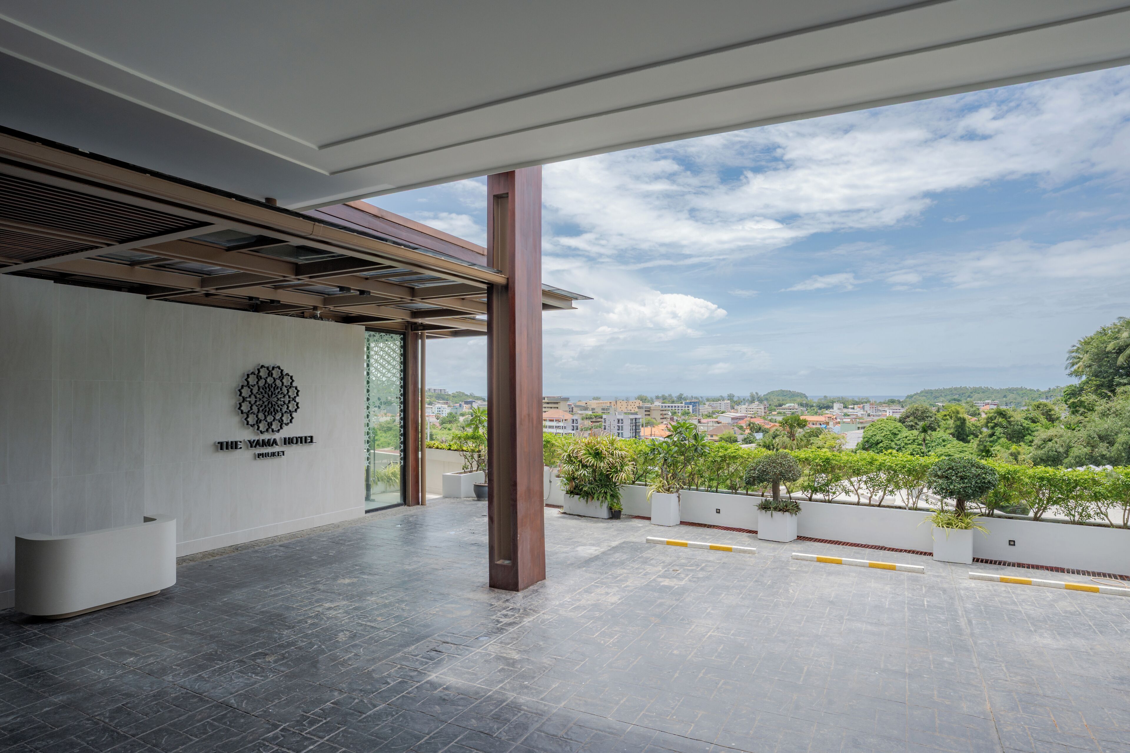 A hotel reception area with a modern design, a view of the cityscape, and a clear sky.