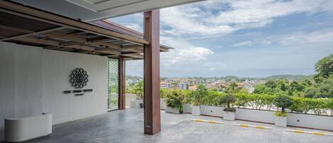 A hotel reception area with a modern design, a view of the cityscape, and a clear sky.