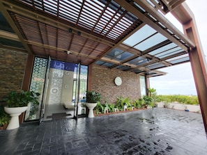 Stunning entrance with a glass door, decorative metal frame, and steps leading up to a brick building with a clock.