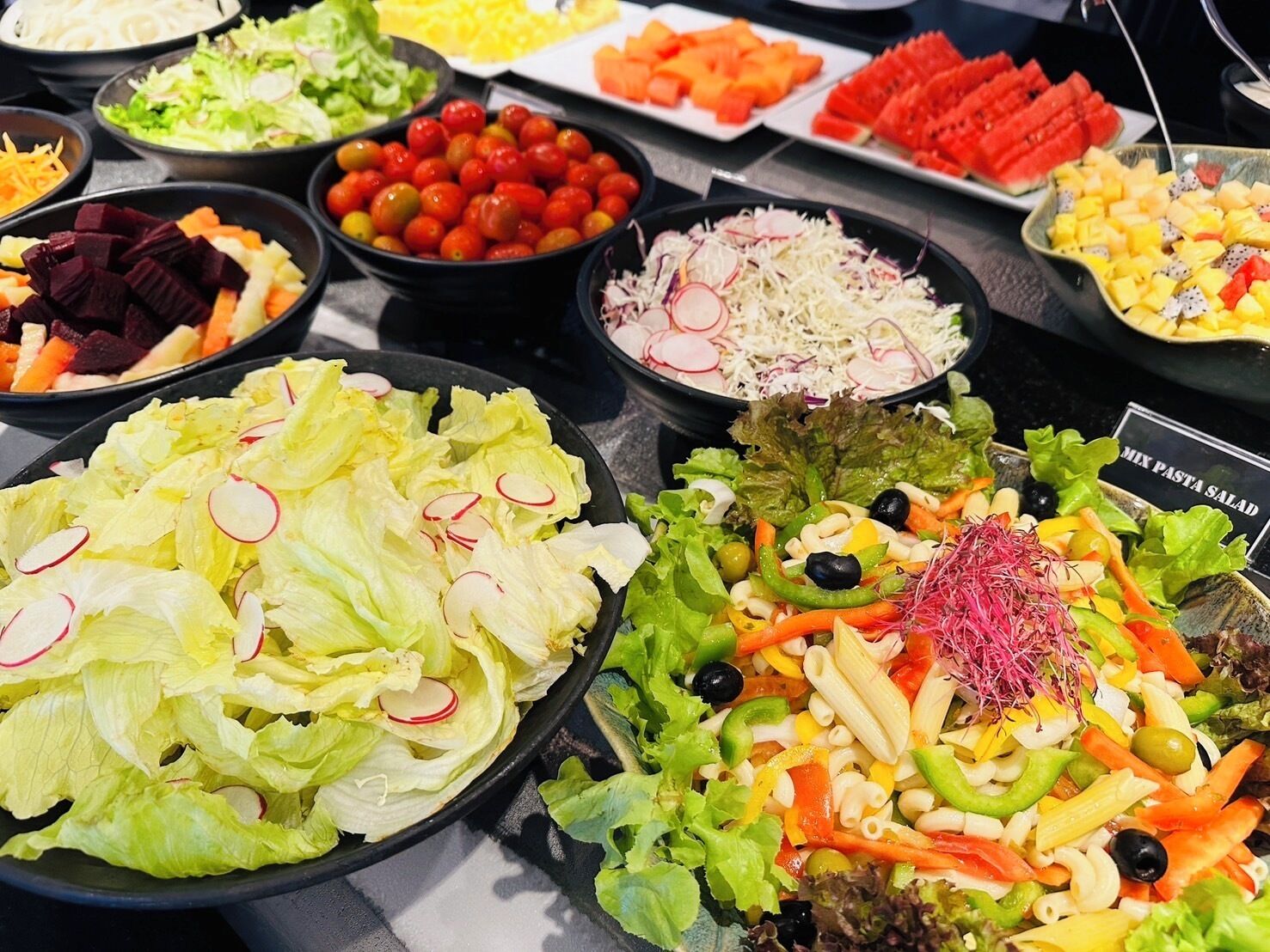 Un bufé con ensaladas y frutas variadas.