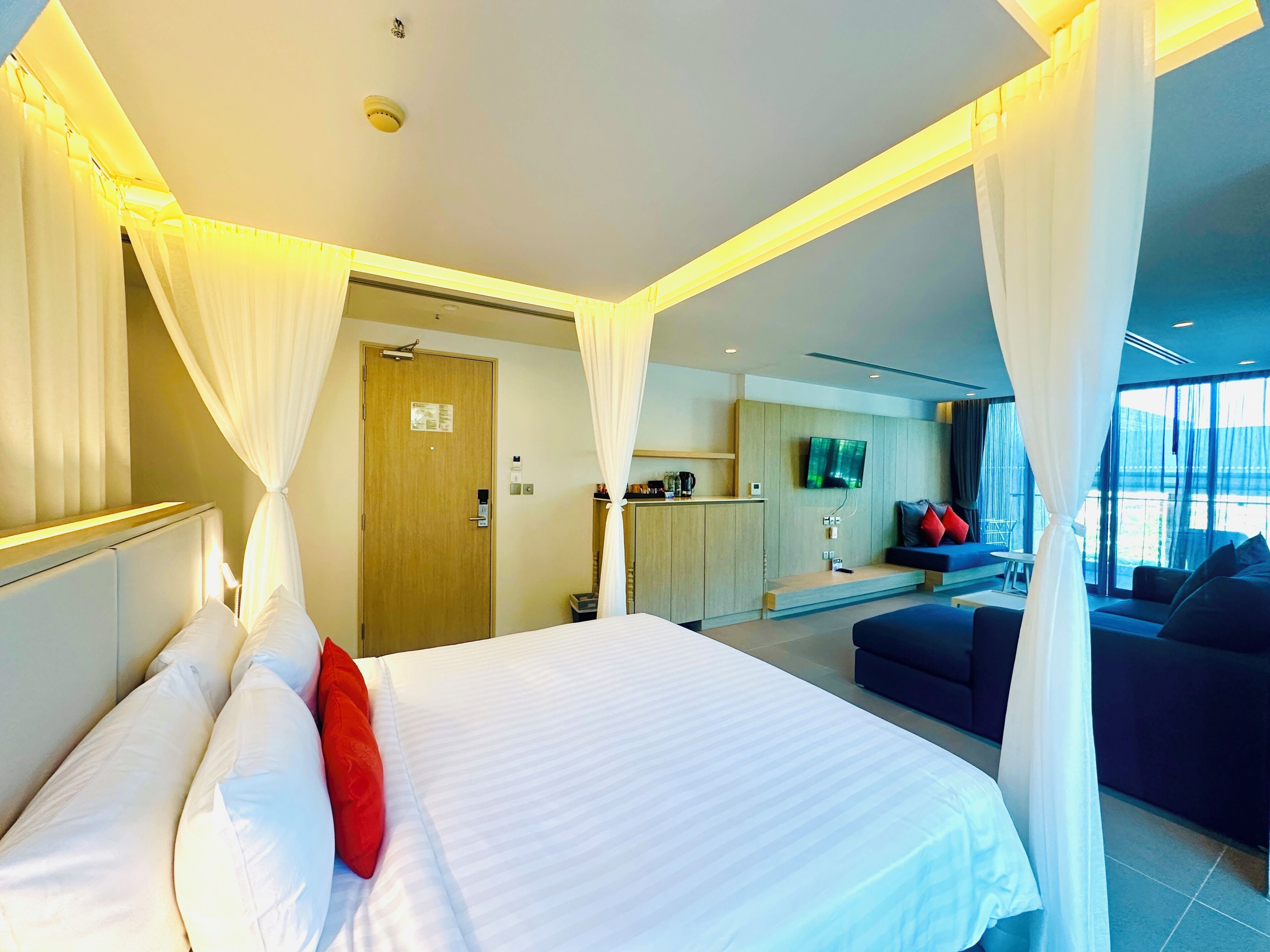 A hotel room with a bed, a TV, a sofa, and a desk.