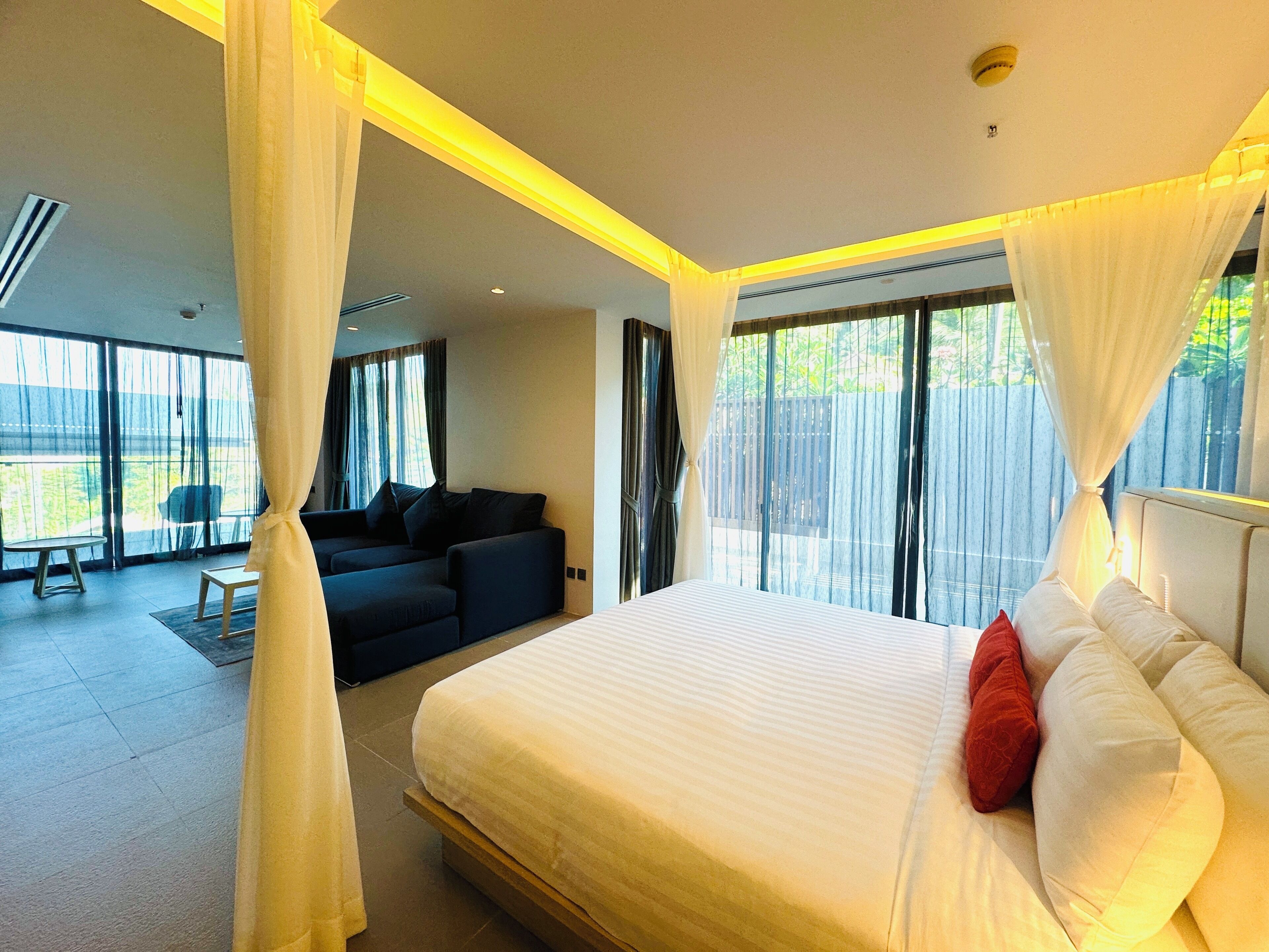 Un dormitorio con una cama grande, un sofá y vistas al exterior.