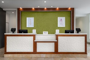 Un mostrador de recepción con una pared verde con textura, dos cuadros enmarcados y un letrero de 'Hilton Honors'.