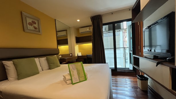 Une chambre d’hôtel avec un grand lit, un téléviseur à écran plat, un bureau et une fenêtre donnant sur l’extérieur.