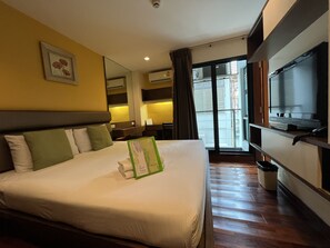 Habitación de hotel con una cama grande, un televisor de pantalla plana, un escritorio y una ventana con vistas al exterior.