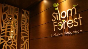 Une enseigne pour la « Résidence exclusive Silom Forest », avec un design moderne et des panneaux décoratifs en bois.