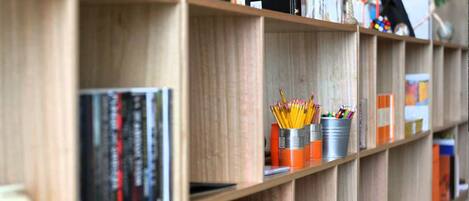 A bookshelf with books and metal containers holding pencils and pens.