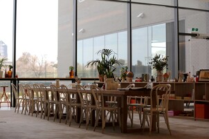Un comedor moderno con una mesa larga, sillas, ventanas amplias y plantas en macetas.
