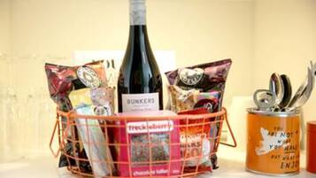 A basket containing snacks, a bottle of wine, and a canister.