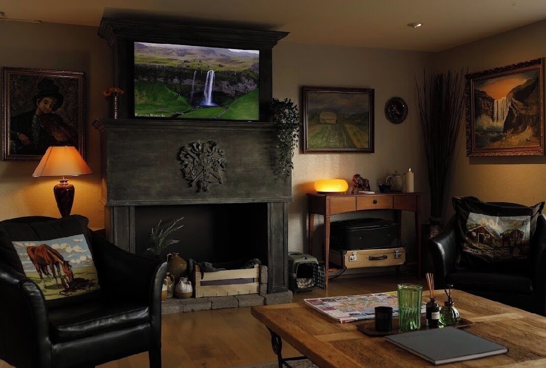 Una sala de estar con chimenea, televisor montado sobre ella y una mesa de centro con libros y objetos decorativos.