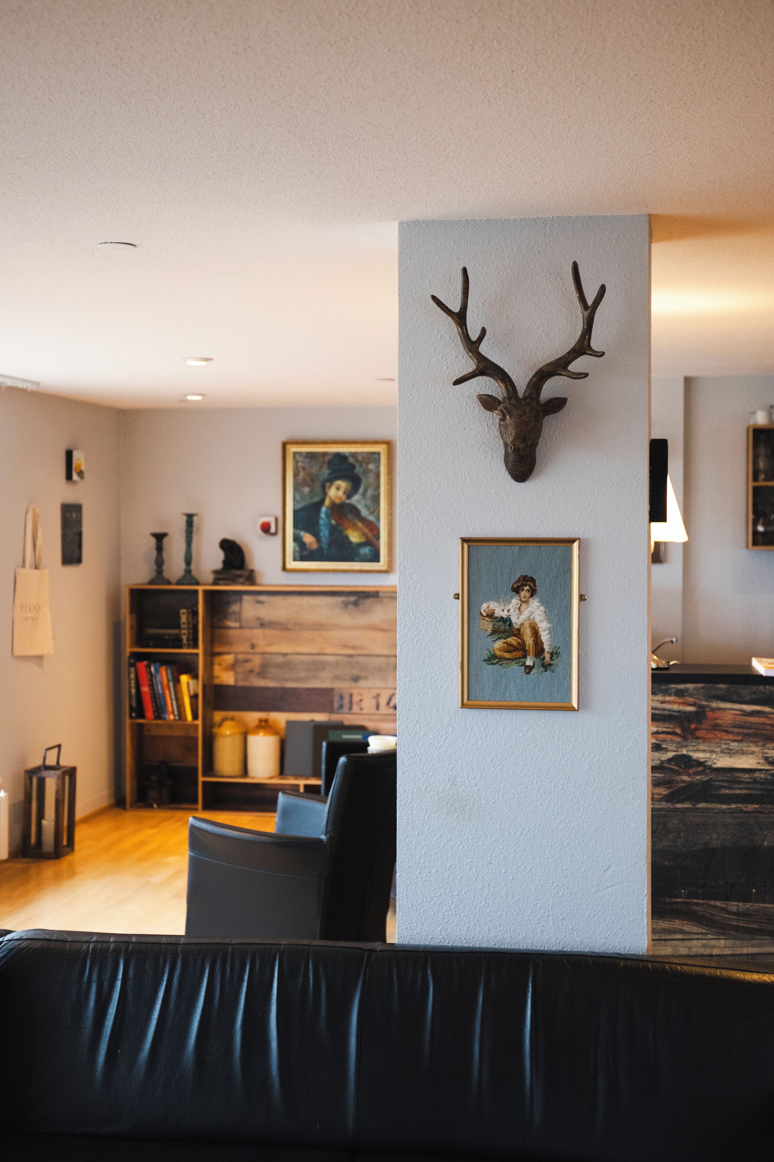 A living room with a mounted deer head, a bookshelf, and framed artwork on the wall.