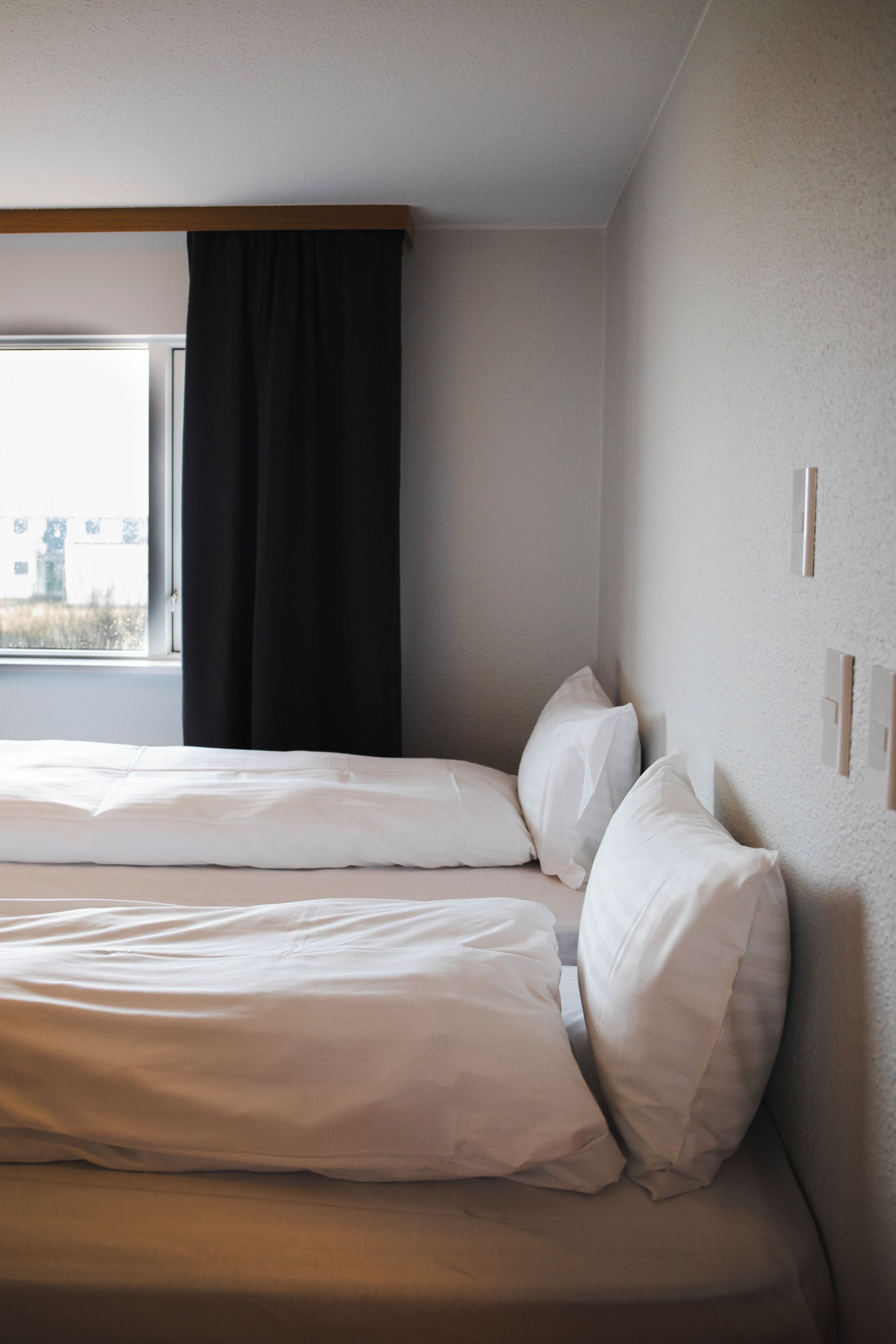 A hotel room with two beds, a window with a view, and a curtain.