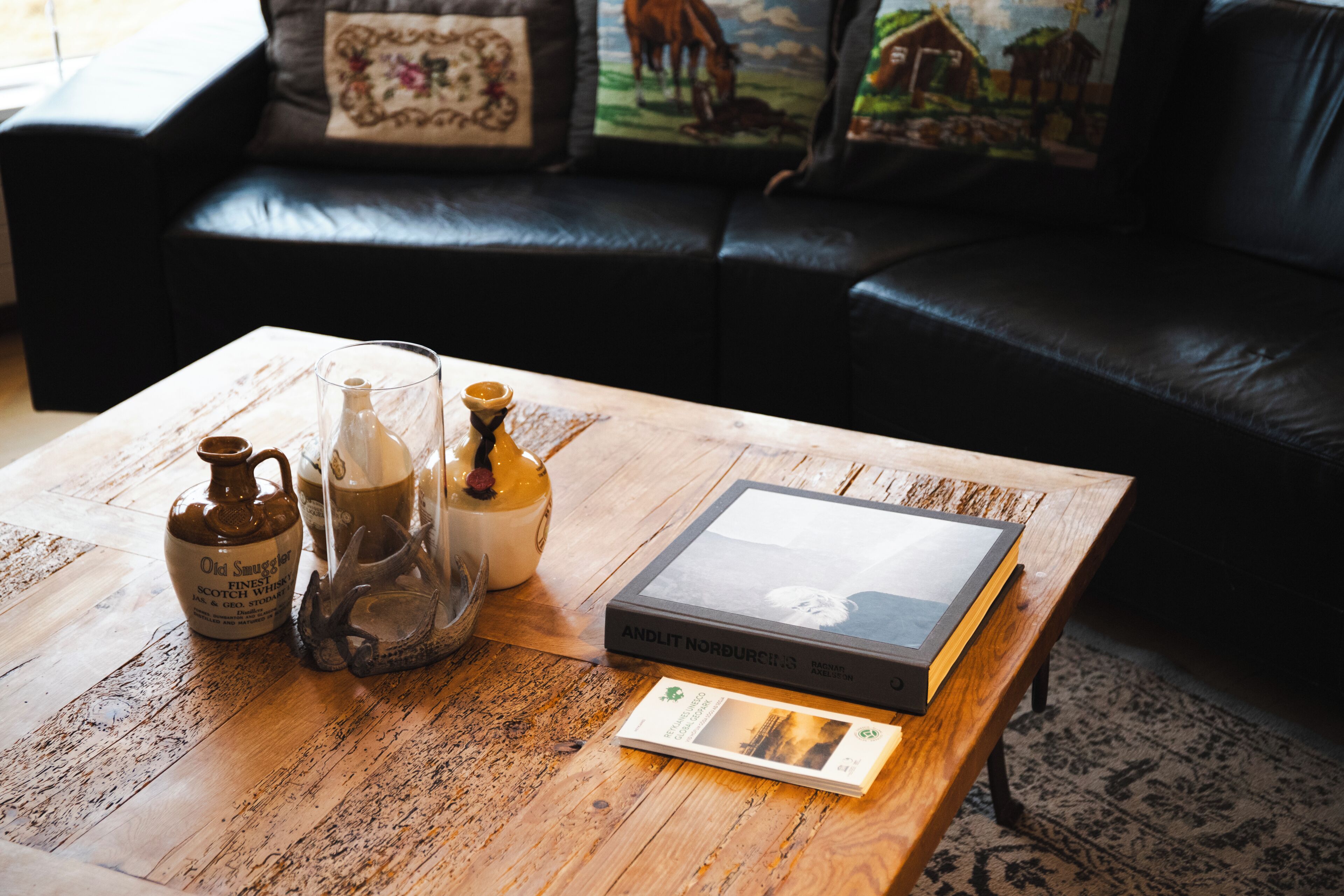 Une table basse en bois sur laquelle se trouvent un livre, une carafe en verre et un pichet.