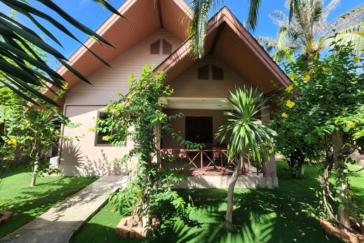 Una casa amb teulada inclinada, un porxo i un jardí ben cuidat.