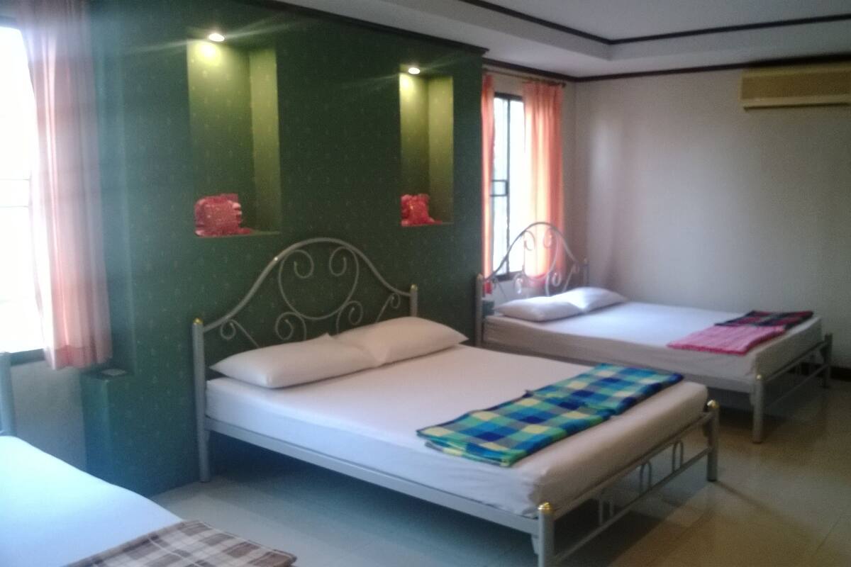 A room with two single beds, a small table, and a chair.