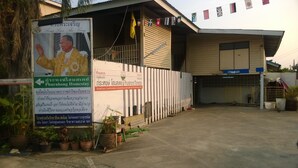 A building with a sign for Phurahong Homestay, featuring a check-in area and a gated entrance. - Phurahong Homestay (Bangkok)