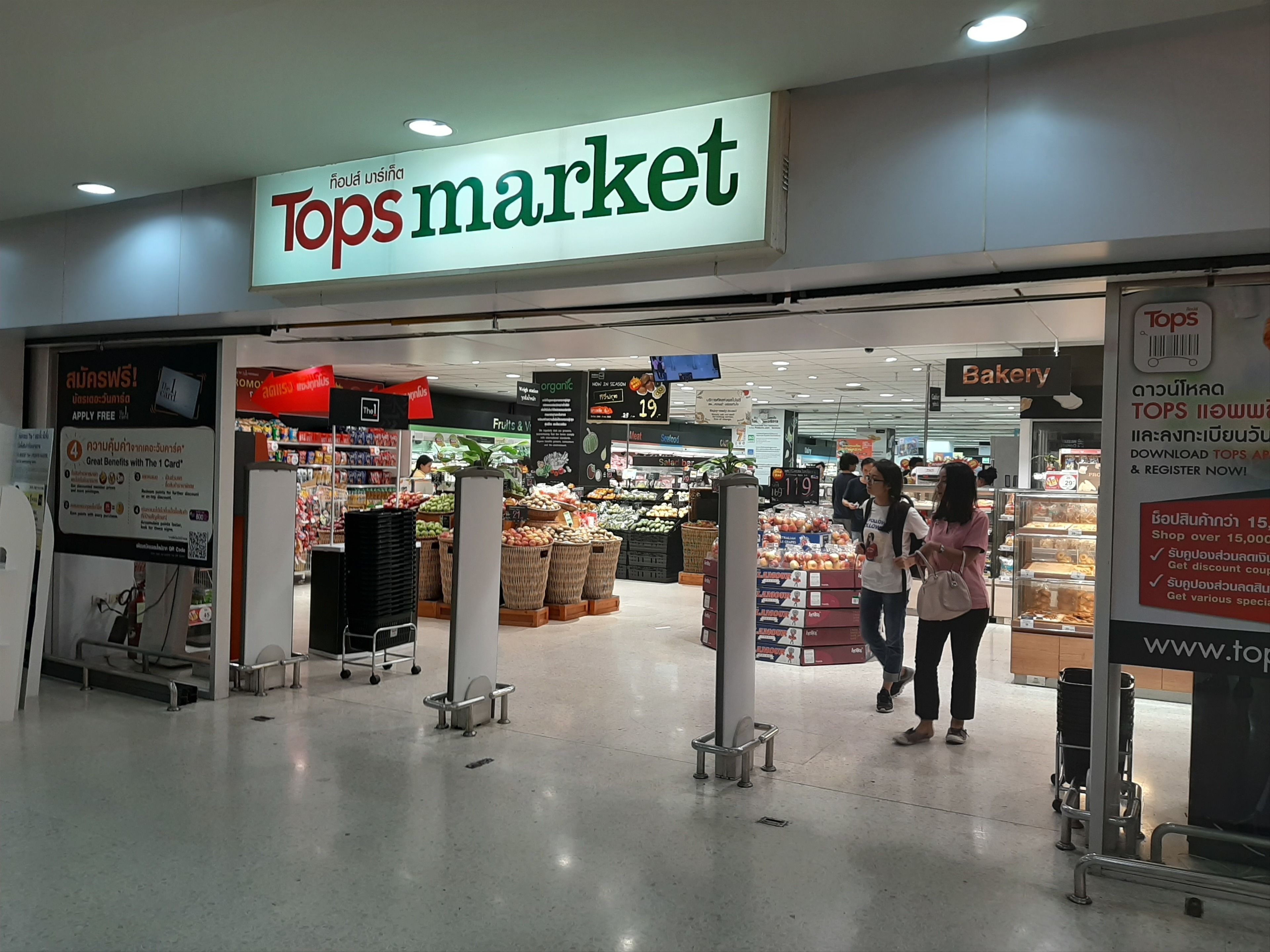 Der Eingang zum Tops Market mit einem Schild darüber und einem Blick auf den Backbereich im Inneren.
