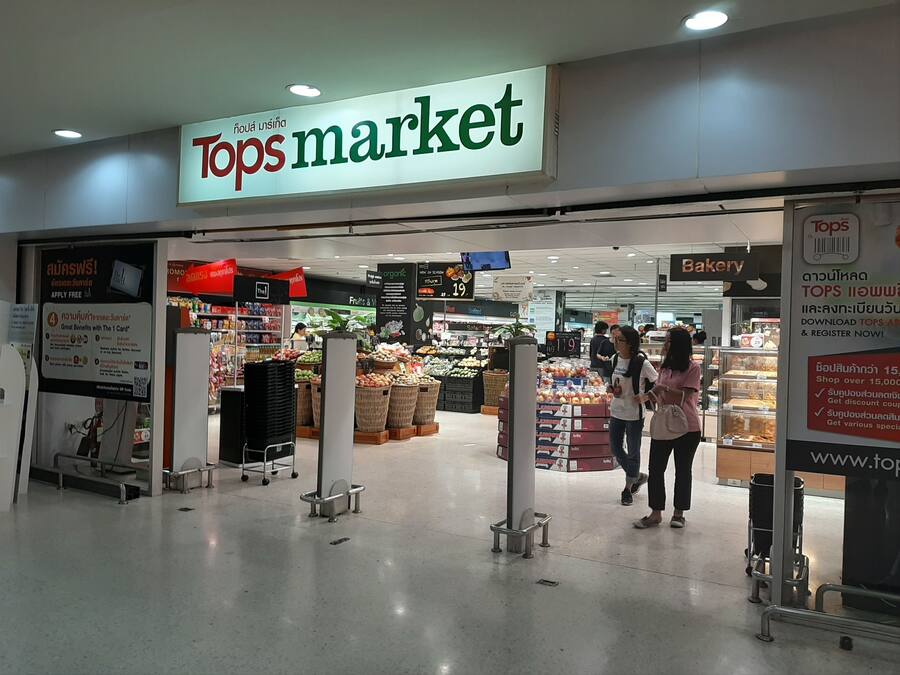 La entrada a Tops Market, con un cartel sobre la puerta y una sección de panadería visible en el interior.
