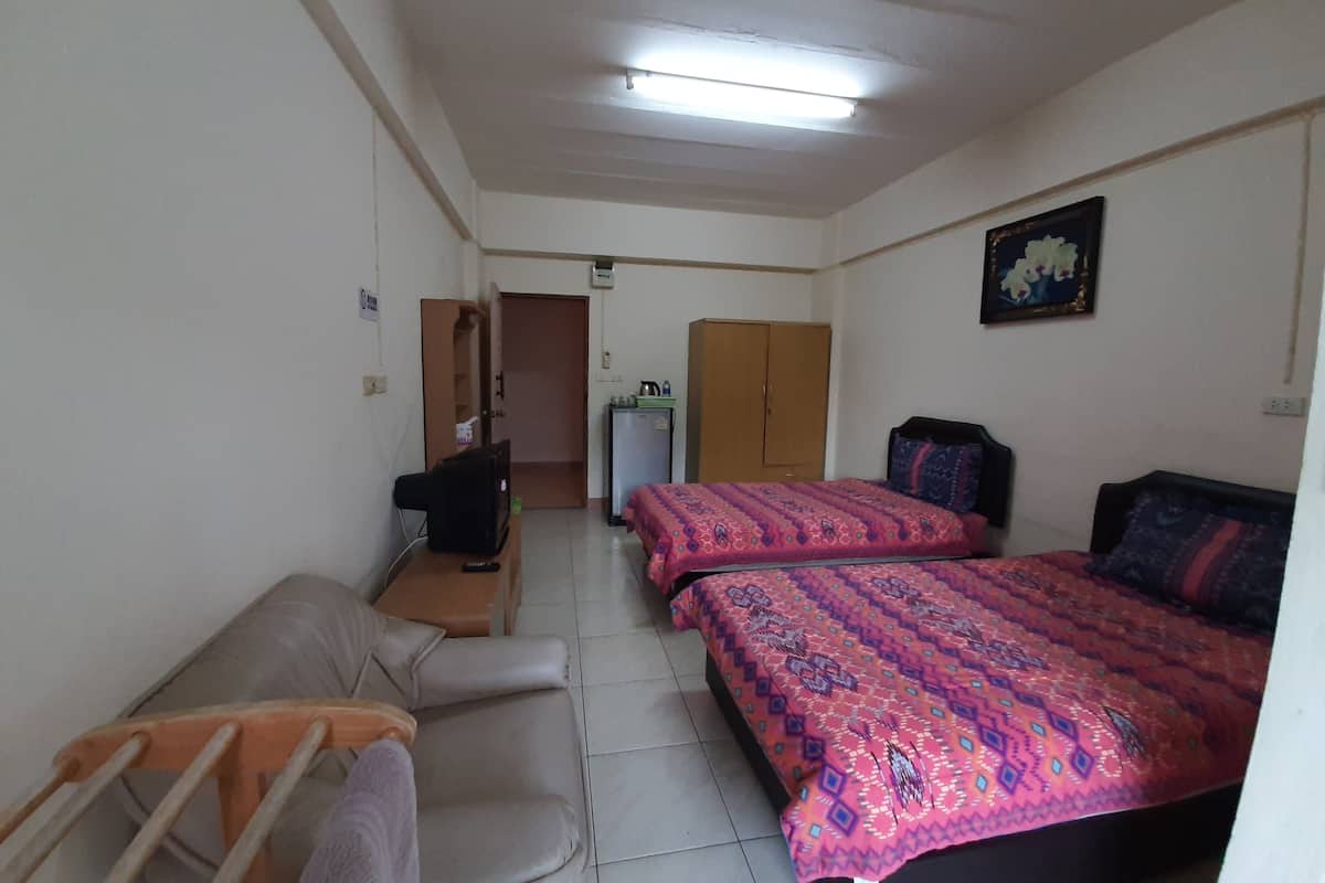 A small, well-lit room with two beds, a sofa, a desk, and a wardrobe.