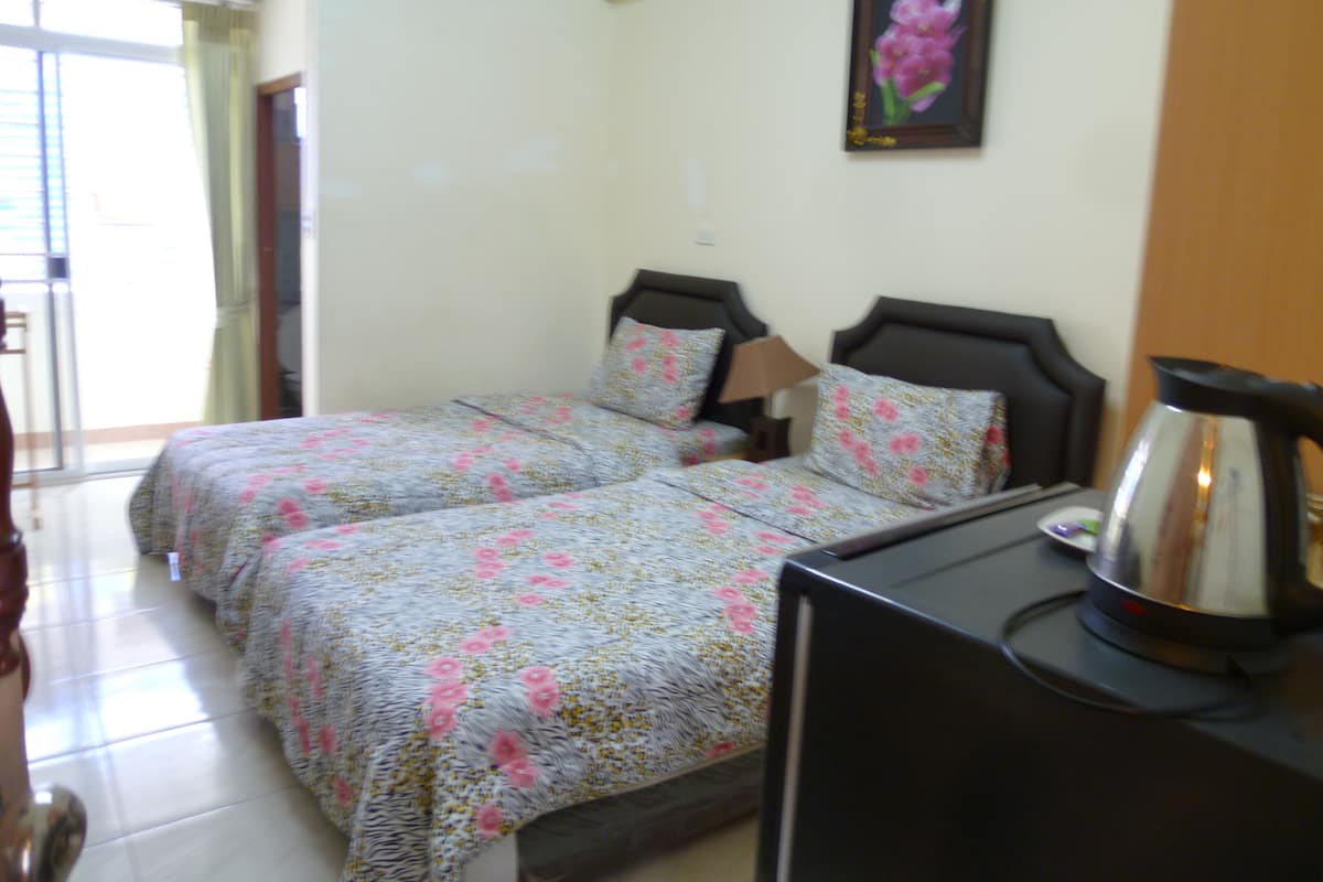 A hotel room with two beds, a coffee maker, and a painting on the wall.