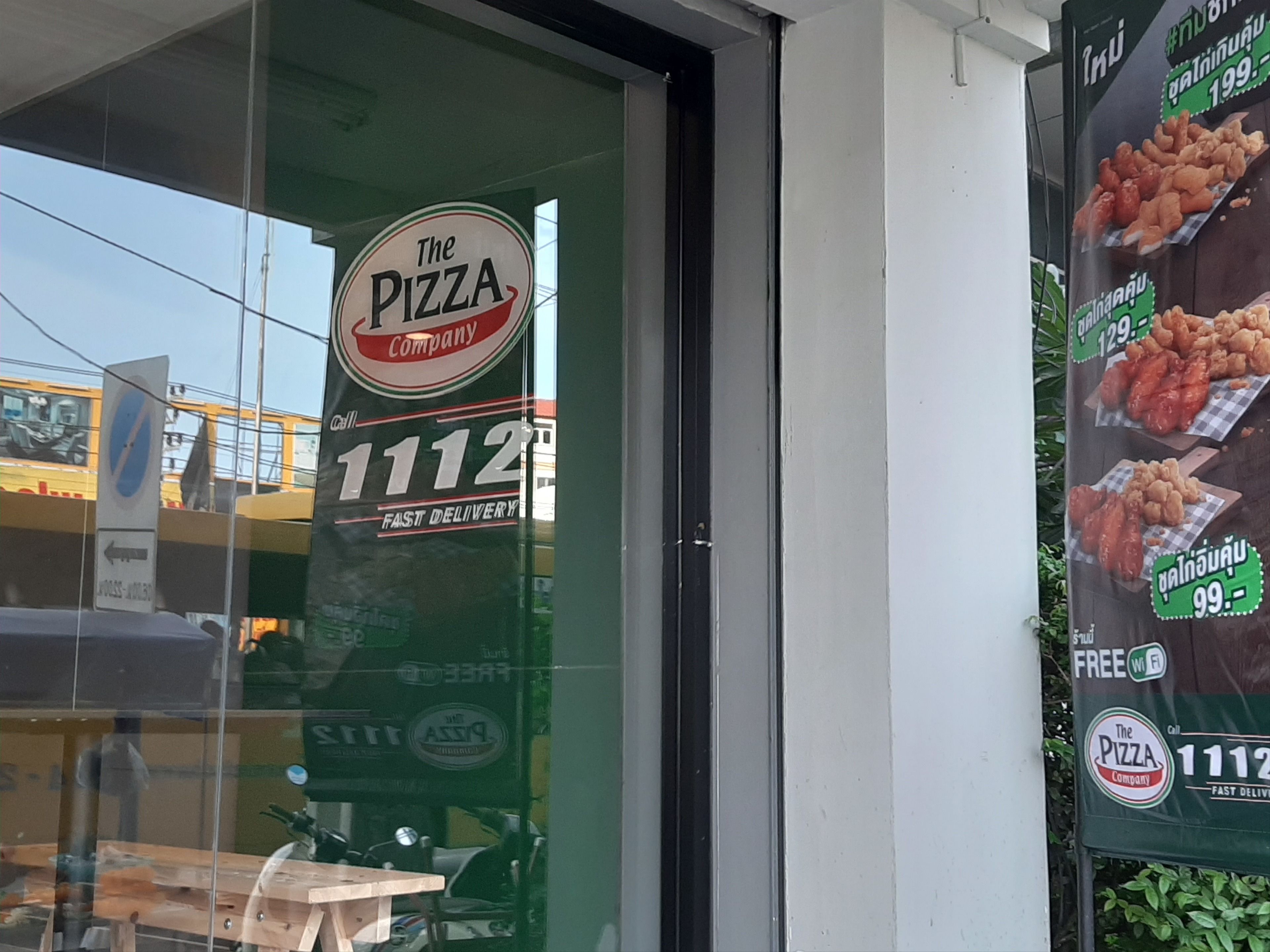 A storefront with a pizza company sign, a contact number, and a menu board advertising free Wi-Fi.