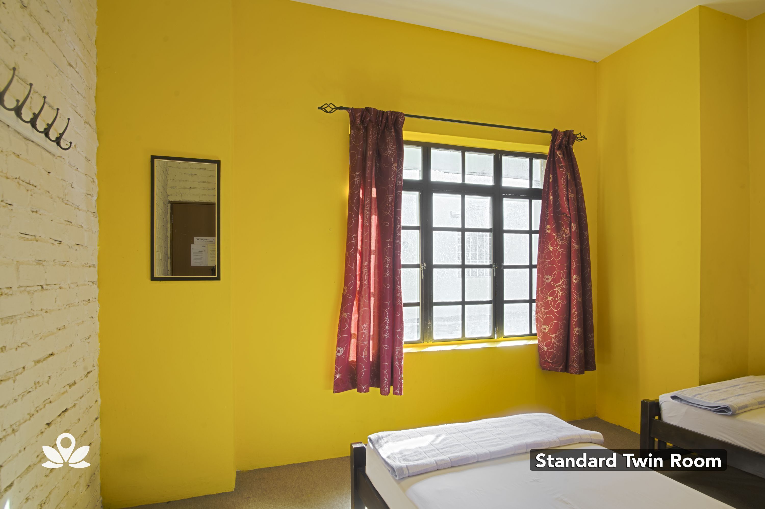 A standard twin room with a window, a bed, and a wall-mounted picture.