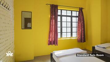A standard twin room with a window, a bed, and a wall-mounted picture.