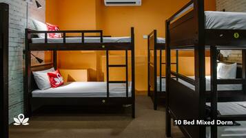 Un dormitorio mixto para 10 personas con literas, una pared de ladrillo, un equipo de aire acondicionado y una lámpara.