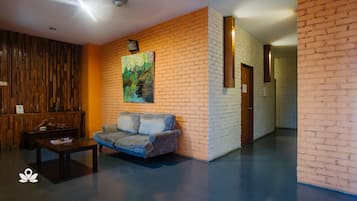 Un lobby moderno con una pared de madera, un sofá azul, una mesa de centro y un cuadro de un bosque.