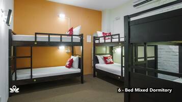 A dormitory with bunk beds, a wall-mounted air conditioner, and a light fixture.
