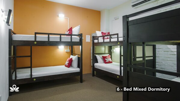 A dormitory with bunk beds, a wall-mounted air conditioner, and a light fixture.